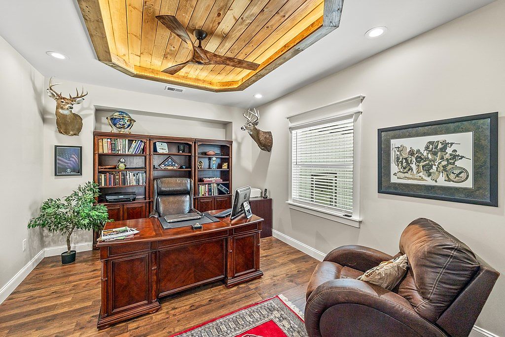 Home office with a custom inset cedar tray ceiling, built-in bookcases, leather club chair, and rich walnut hardwood floors.