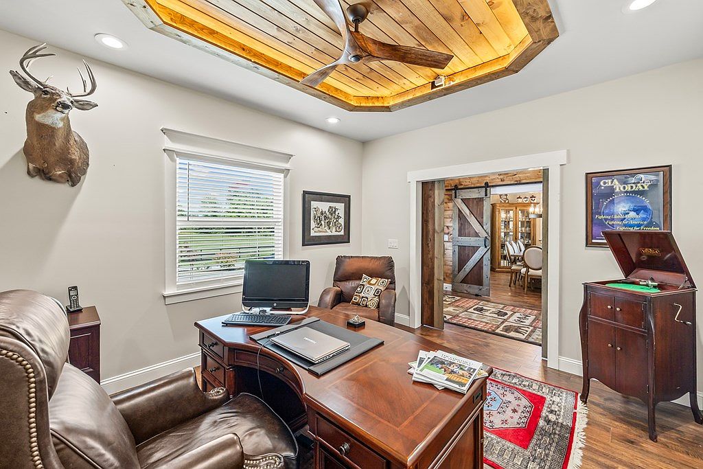 Second view of the office showing the cedar tray ceiling, the second barn-door passage to the formal dining room beyond, and the window letting Tennessee light into the room.